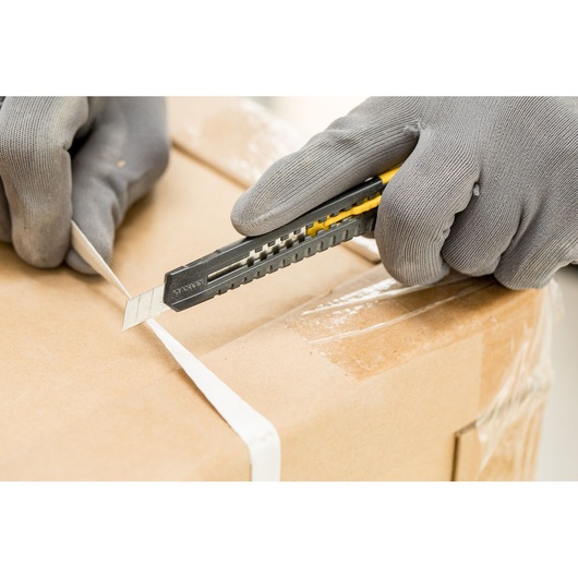STANLEY 0-10-150 utility knife cutting white strap on cardboard box, handheld, close-up photography.