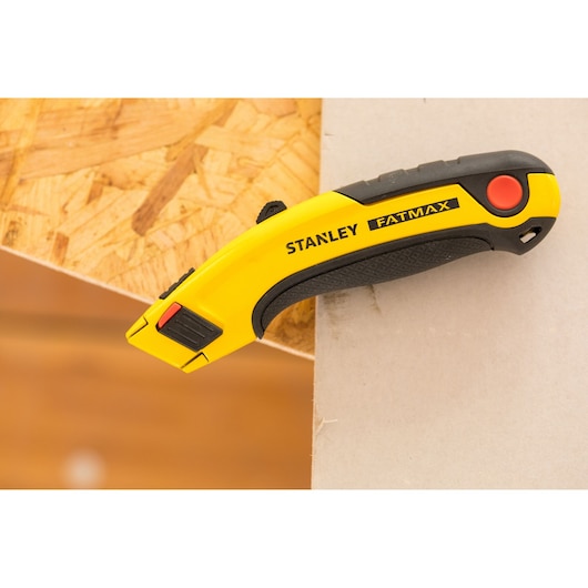 STANLEY 0-10-778 utility knife yellow and black with ergonomic handle on edge, side angle.