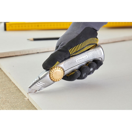 STANLEY 0-10-818 utility knife with gold wheel, cutting board, photography of gloved hand in action.
