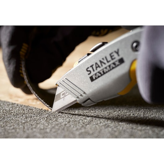STANLEY 0-11-800 utility knife cutting carpet, close-up photography with gloved hand.