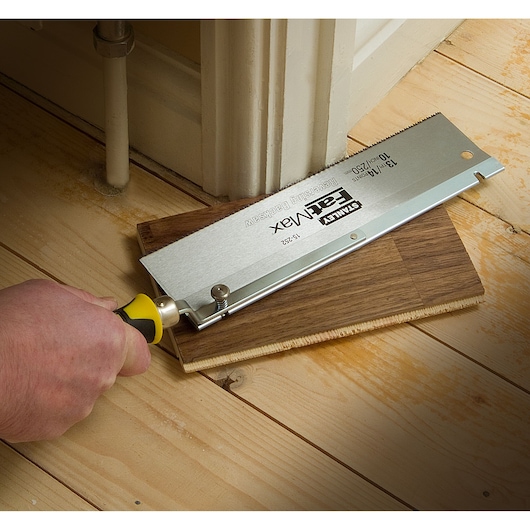 STANLEY 0-15-252 flush cut saw cutting laminate flooring near a door frame, close-up angle.