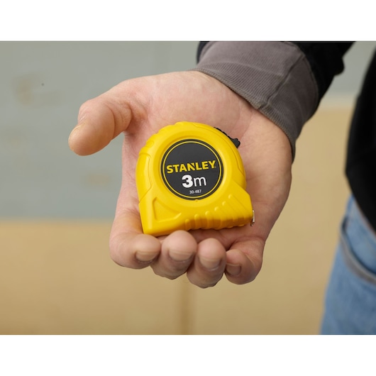 STANLEY 0-30-487 yellow 3m tape measure held in hand, clear product branding visible.