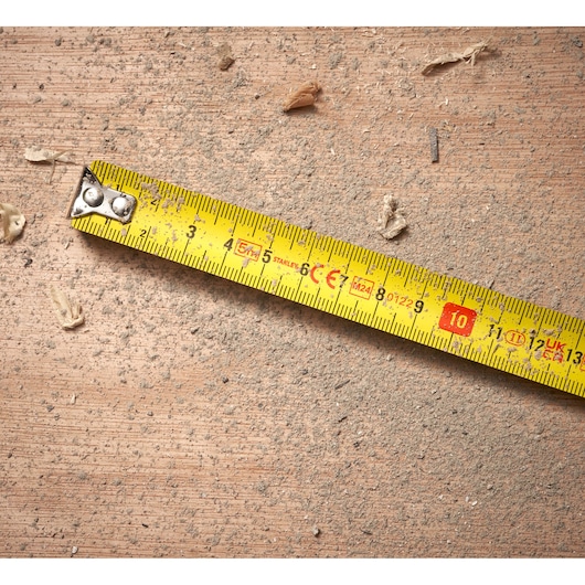 STANLEY 0-30-697 yellow tape measure on dusty wood surface, product photography.