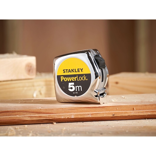 Stanley 0-33-195 tape measure, PowerLock, 5m length, chrome finish, photography on wood surface.