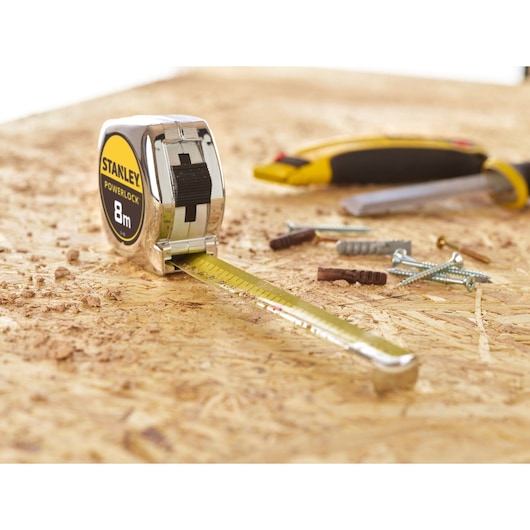 STANLEY 0-33-198 tape measure on workbench, extended, with screws and hand tools in background.