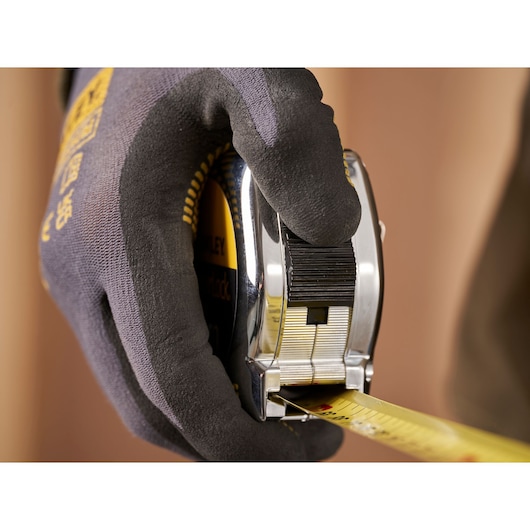 Photo of STANLEY 0-33-198 tape measure in gloved hand, measuring yellow tape extended.