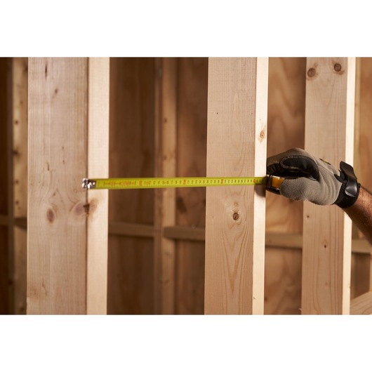 STANLEY 0-33-238 tape measure in use measuring wooden framing, close-up side view.