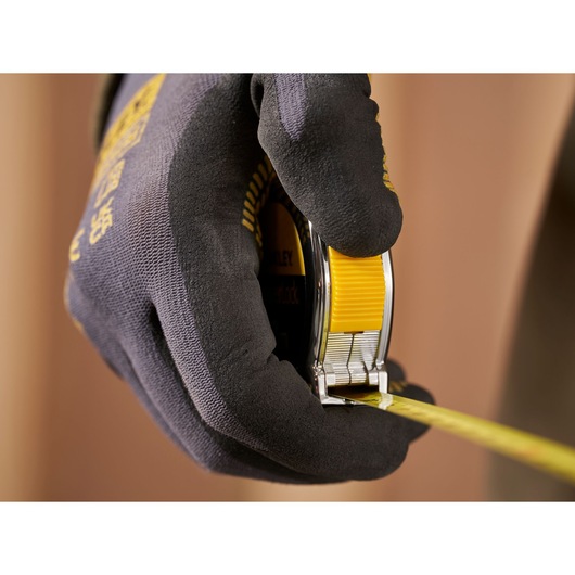 Photo of STANLEY 0-33-238 tape measure in gloved hand, yellow lock button visible, close-up view.