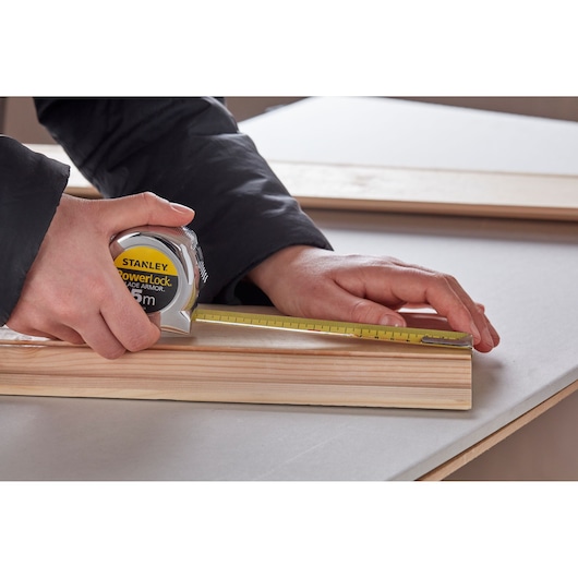Photo of STANLEY 0-33-514 tape measure being used to measure a wooden board on a table.