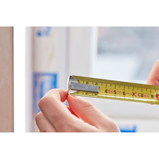 STANLEY 0-33-514 tape measure in use, close-up showing yellow measuring tape and metal hook.