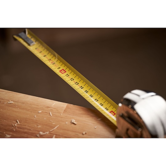 STANLEY 0-33-514 tape measure in use on wood surface, yellow blade with clear metric markings.
