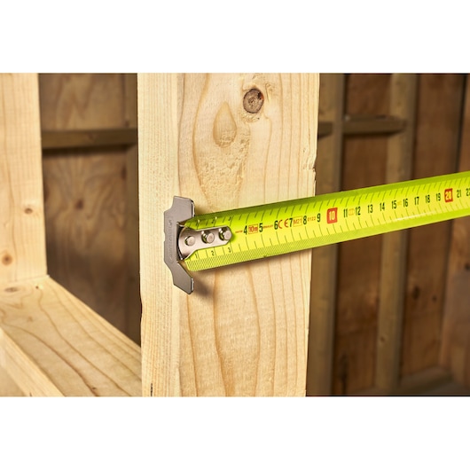 STANLEY 0-33-897 tape measure with yellow blade measuring wood plank, close-up angle.