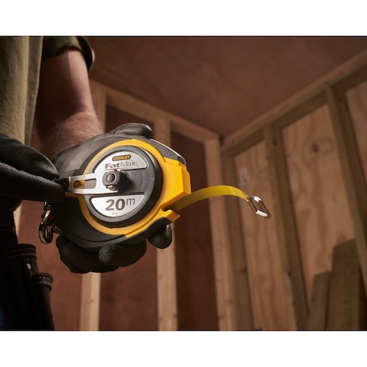 Photo of STANLEY 0-34-133 FatMax 20m tape measure held by gloved hand in construction setting.