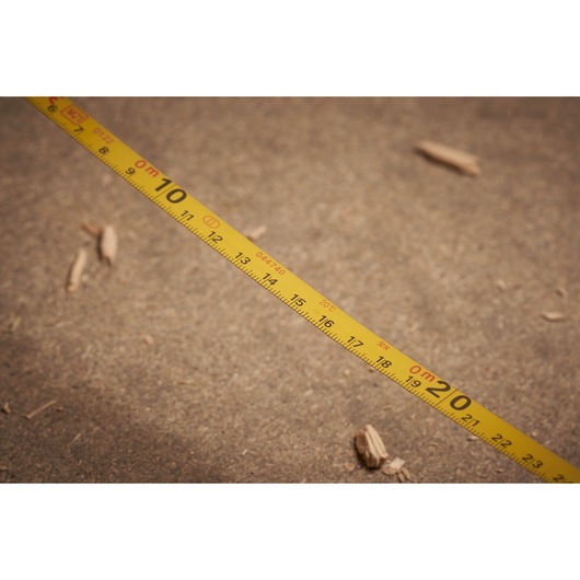 STANLEY 0-34-133 yellow measuring tape with black markings, photography on sandy surface.