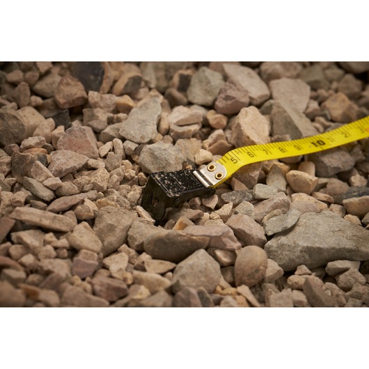 STANLEY 0-34-297 yellow tape measure on rocky ground, close-up photography of product end.