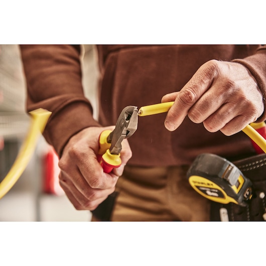 STANLEY 0-84-004 pliers cutting yellow cable, close-up photography, tool visible with tape measure.