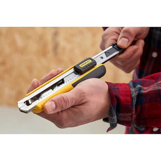 Photo of STANLEY 1-10-481 utility knife with yellow handle in use, close-up view.
