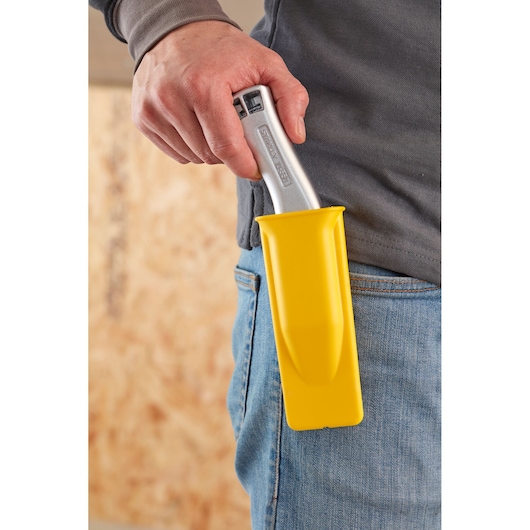 STANLEY 1-10-550 utility knife in yellow holster clipped to jeans, close-up side view.
