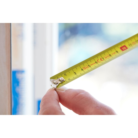 STANLEY 1-30-497 yellow tape measure held in hand, close-up, product photography.