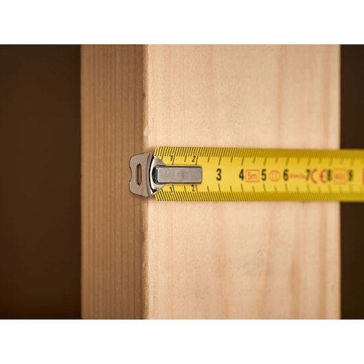 STANLEY 1-33-194 tape measure measuring wooden plank, close-up side angle.