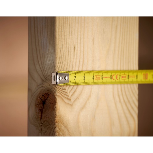 STANLEY 1-33-238 yellow tape measure extended against wooden beam, close-up angle.