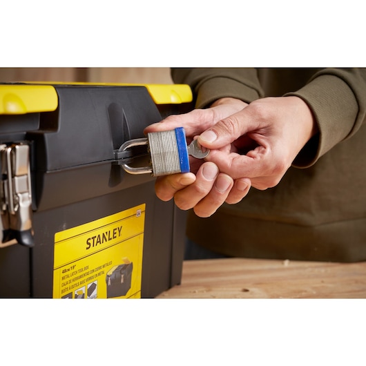 Photo of STANLEY 1-92-066 tool box being locked with a silver padlock, close-up of hands and lock.