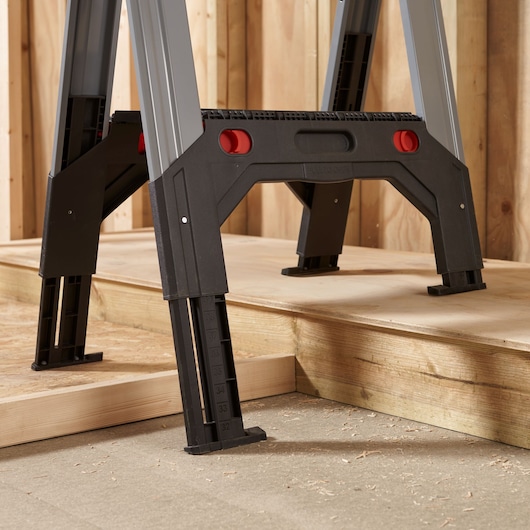 STANLEY 1-92-980 adjustable work platform legs with measurement markings, close-up side angle, on wooden floor.