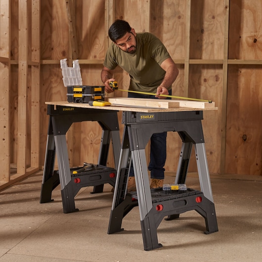 Photo of STANLEY 1-92-980 sawhorse pair used as workbench in a workshop with tools and wood plank.