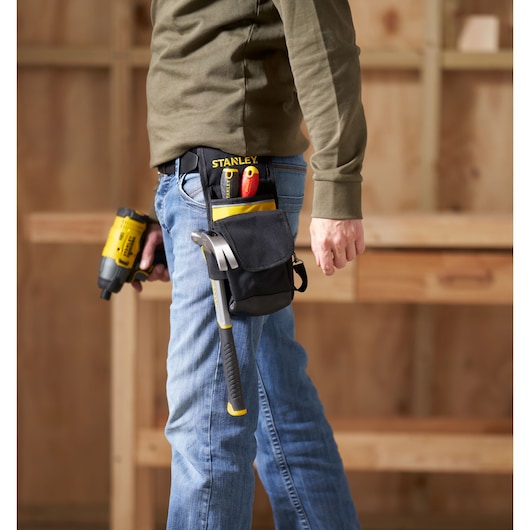 STANLEY 1-93-329 tool pouch with hammer, screwdrivers, and utility knife attached to a belt, side angle, workshop background.