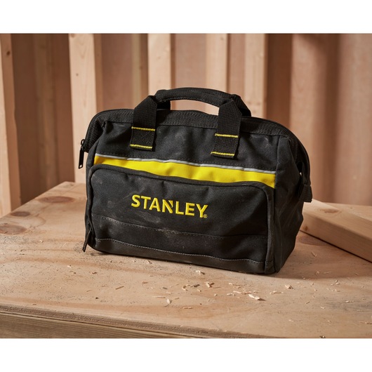 STANLEY 1-93-330 black and yellow tool bag with handles on a wooden workbench, front angle.