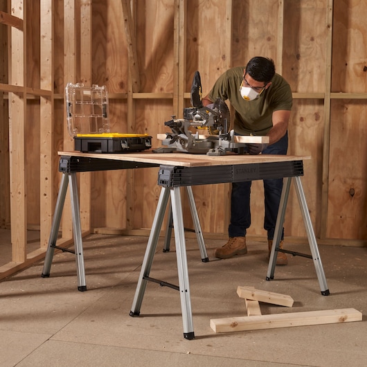 Photo of STANLEY 1-97-475 metal sawhorses used as a workbench in a wooden frame construction site.
