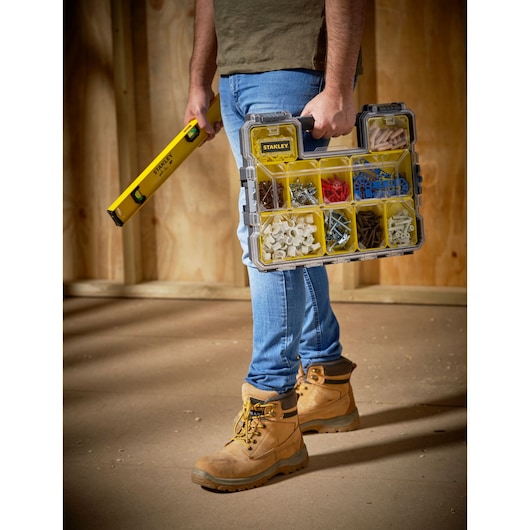 STANLEY 1-97-519 organizer box with yellow compartments, carried by person wearing work boots.