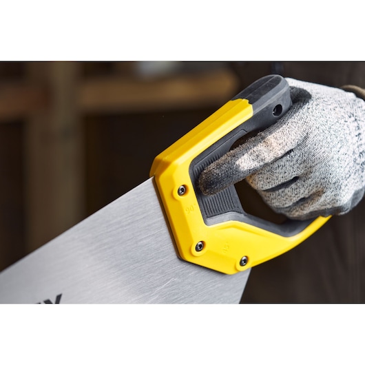 STANLEY 2-15-244 handsaw with yellow and black handle close-up, being held by a gloved hand.