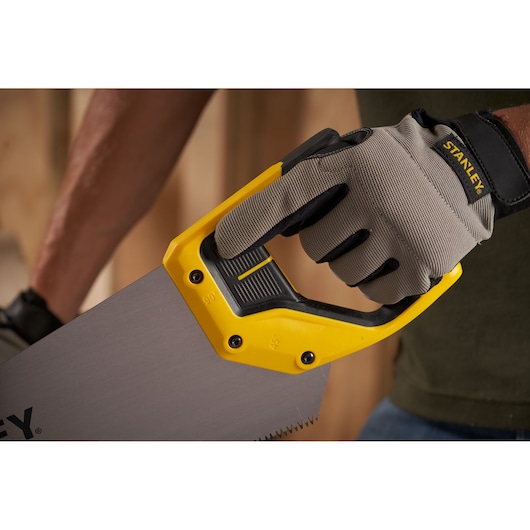 Photo of STANLEY 2-15-599 hand saw with yellow and black handle held by a gloved hand, product in use.