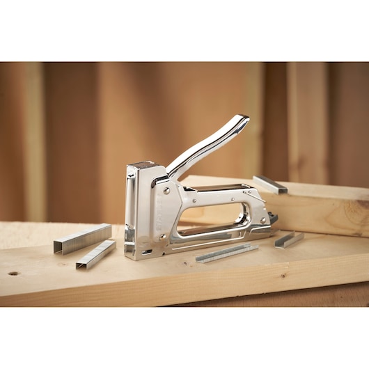 STANLEY 6-TR45 manual staple gun on wood with metal staples, side angle, photography.