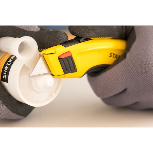 STANLEY 7-10-778 utility knife cutting plastic tube, close-up, photography of product in use.
