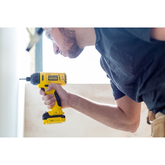 Photo of STANLEY FMC041S2 cordless drill in use, yellow and black design, held by a person.