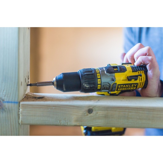 STANLEY FMC625D2 cordless drill being used to drive a screw into wood, close-up side view.