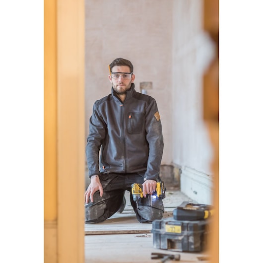 STANLEY FMC647D2 cordless drill in use on job site, worker kneeling with drill, toolboxes on floor.