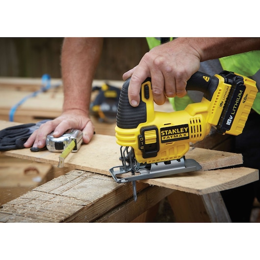 Stanley FMC650M2 cordless jigsaw cutting wood, close-up with worker’s hand.