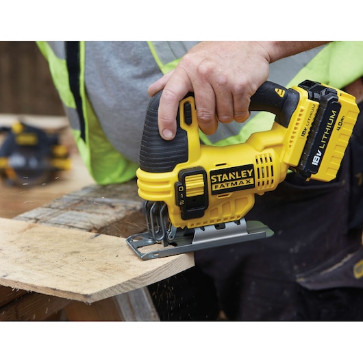 Photo of STANLEY FMC650M2 cordless jigsaw in use cutting wood, yellow and black, FATMAX series, handheld power tool.