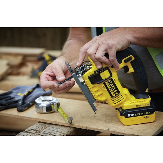STANLEY FMC650M2 jigsaw, yellow and black, being fitted with blade, on wooden workbench.