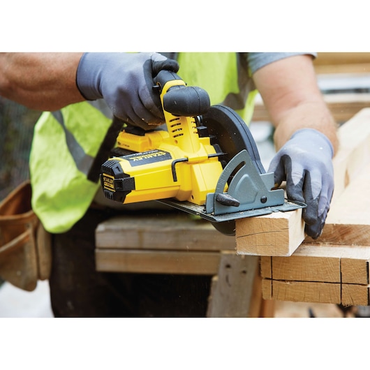 STANLEY FMC660B cordless circular saw cutting wood, close-up with gloved hands, yellow and black tool.