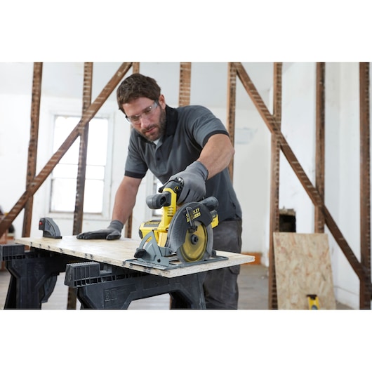 Photo of STANLEY FMC660B circular saw cutting wood, handheld by a person in a construction setting.