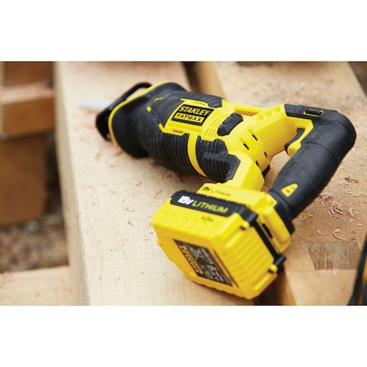 STANLEY FMC675D2 cordless reciprocating saw with yellow and black design on wood, close-up photo.