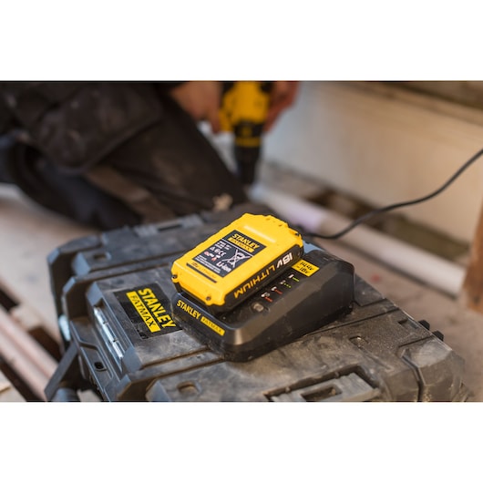 STANLEY FMC692L 18V lithium battery charger on a black toolbox, workshop setting.