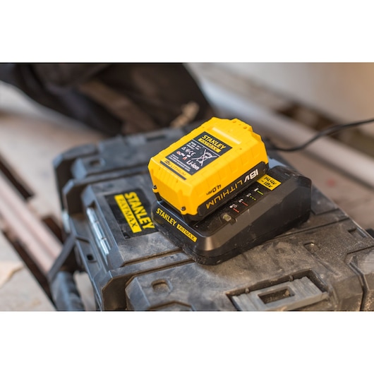 Photo of STANLEY FMC692L battery charger with yellow 18V Li-Ion battery on charging station, angled view.