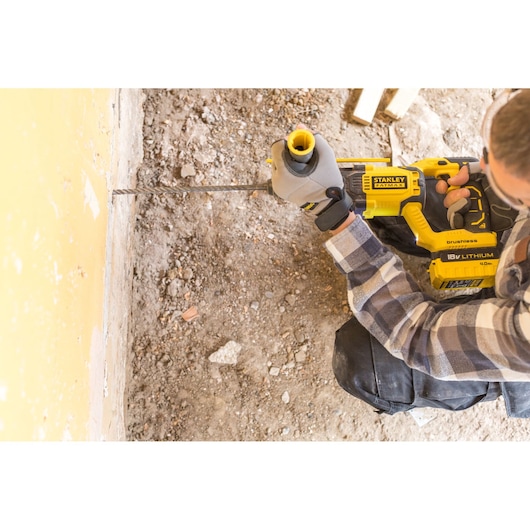 Photo of STANLEY FMCD900M2S cordless rotary hammer drill in use on a masonry wall.