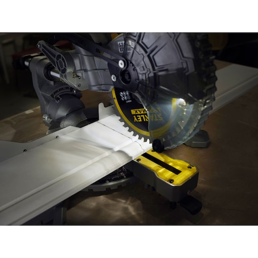 STANLEY FMCS701B miter saw cutting white molding, close-up view of blade and work surface.