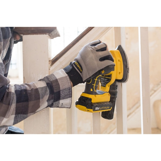 Photo of STANLEY FMCW210B cordless sander, yellow and black, used on white stair railing.